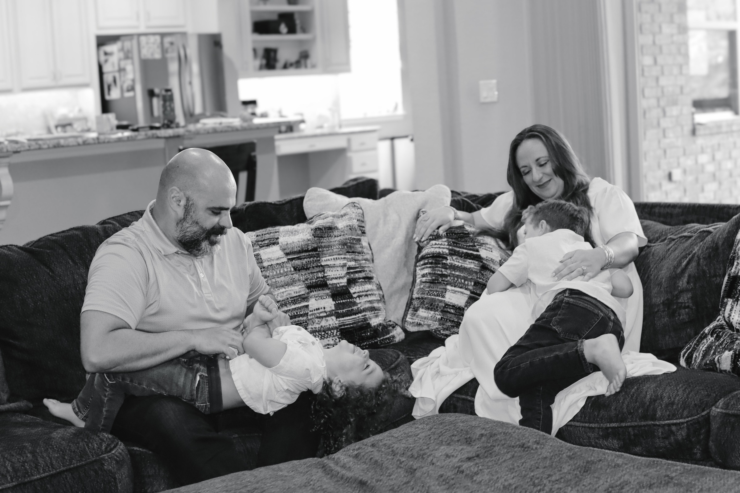 Black and white photograph of a family playing together on the living room couch