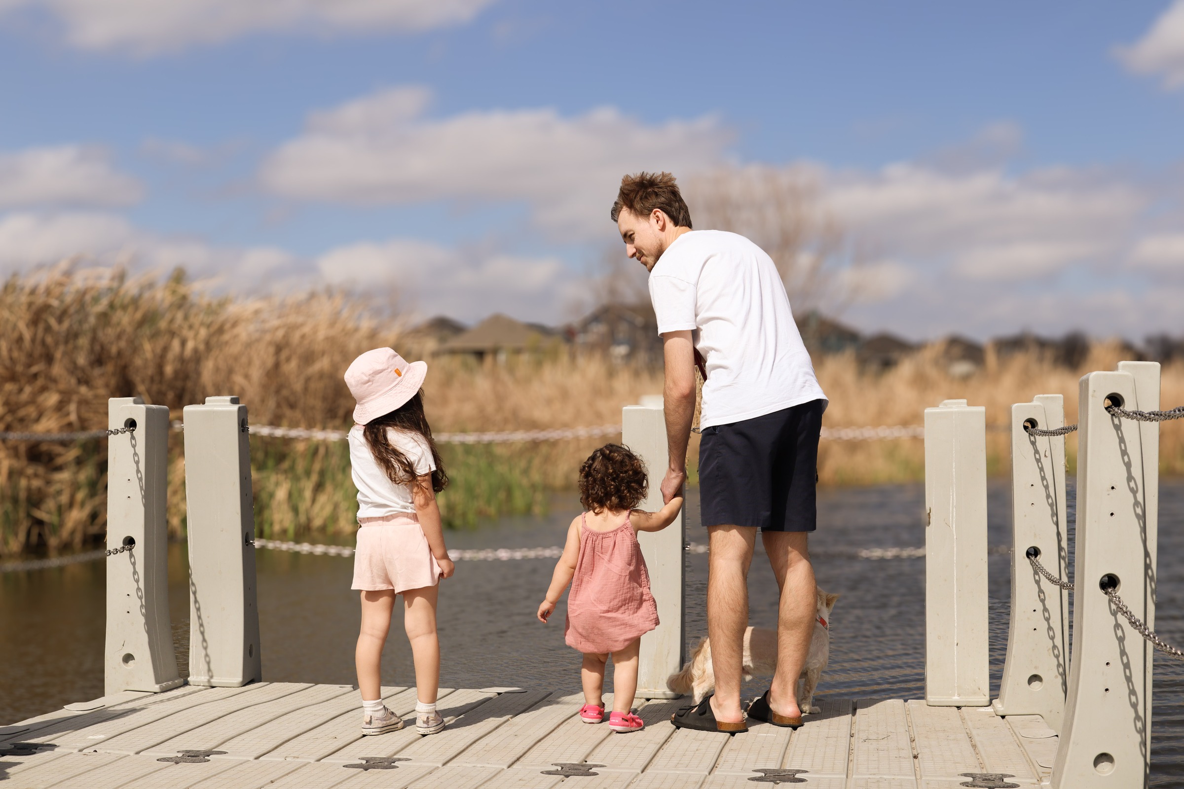 A father and his two daughters looking out over the water from a dock