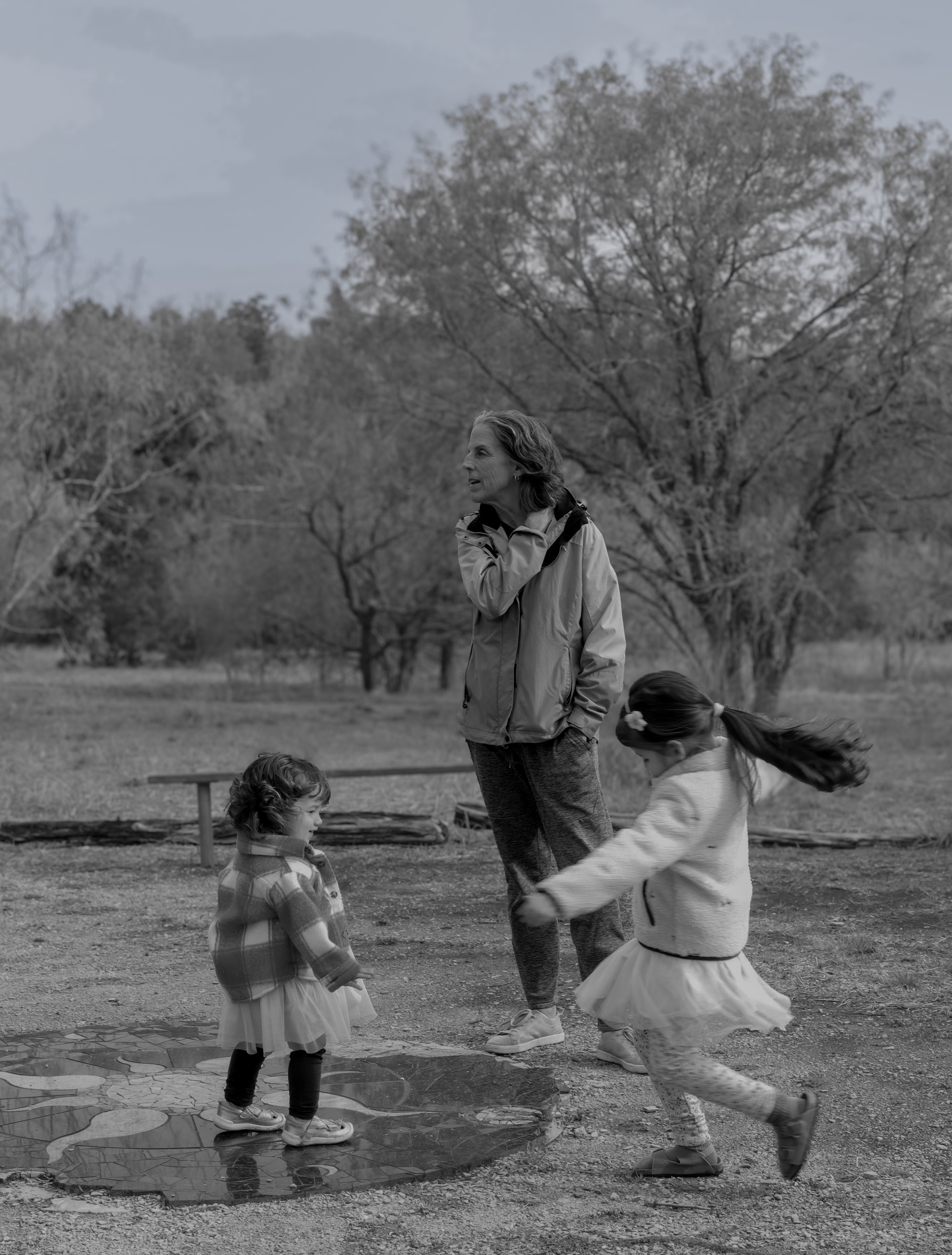 Black and white photograph of a grandmother watching her granddaughters dance and spin